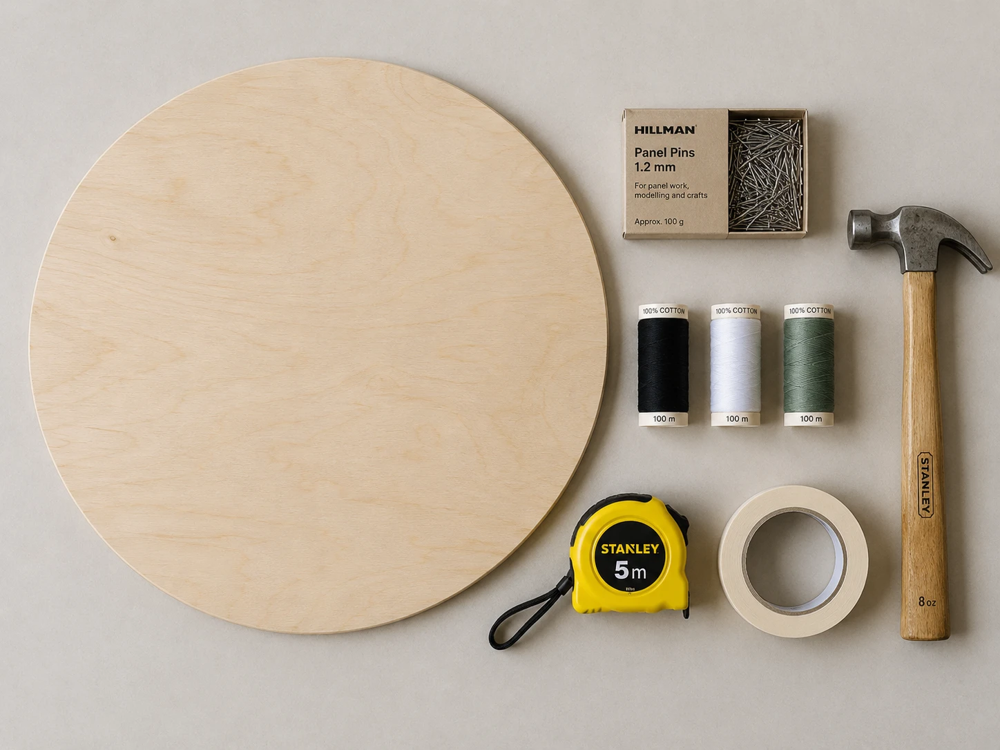 A round birch board, panel pins, cotton spools, a hammer, masking tape and a tape measure
